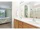 Well-lit bathroom with double vanity and large mirror, view of a bedroom with a large window at 9908 Camino Loma Verde Ave, Las Vegas, NV 89117