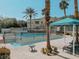 View of the pool area with lounge chairs, palm trees, shaded area, and tropical landscaping at 10001 Peace Way # 2269, Las Vegas, NV 89147
