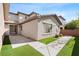 A cozy backyard features synthetic grass, a stone pathway, and white stucco walls at 10505 Howling Coyote Ave, Las Vegas, NV 89135