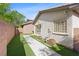 A cozy backyard with synthetic grass, a concrete pathway, and a brick wall at 10505 Howling Coyote Ave, Las Vegas, NV 89135