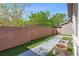 A cozy backyard with synthetic grass, a concrete pathway, and a brick wall at 10505 Howling Coyote Ave, Las Vegas, NV 89135