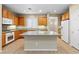 Bright kitchen featuring oak cabinets, granite countertops, a large island, and modern appliances at 10505 Howling Coyote Ave, Las Vegas, NV 89135