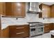 Close-up of the modern kitchen's stainless steel range, vent hood, white countertops, and walnut-colored cabinets at 1136 Jamesbury Rd, Las Vegas, NV 89135