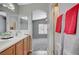 Bathroom featuring double sinks, wood cabinets, and doorway to a bedroom with vaulted ceiling at 1162 Red Margin Ct # 101, Las Vegas, NV 89183