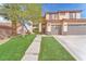 Two-story home with three-car garage, mature landscaping, and a walkway leading to the front door at 1304 Autumn Wind Way, Henderson, NV 89052