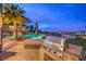 Poolside barbeque area with a built-in grill, palm trees, and scenic views at 1377 Ruby Sky Ct, Henderson, NV 89052