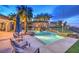 Inviting pool area with lounge chairs, waterfall, lighting, and lush landscaping at 1377 Ruby Sky Ct, Henderson, NV 89052