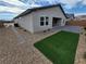 Landscaped backyard featuring an artificial lawn, stone pathways, and a neutral stucco exterior at 247 Desoto Falls St, Indian Springs, NV 89018