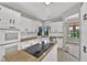 Bright kitchen featuring white cabinets, granite countertops, stainless steel appliances, and a central island with cooktop at 2714 Bridgepointe Dr, Las Vegas, NV 89121