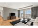 Living room with light gray walls, wood floors, a large window, a gray sectional, and a dark rug at 3750 Las Vegas Blvd # 3008, Las Vegas, NV 89158