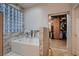 Bathroom with a soaking tub, glass block window, and access to a walk-in closet at 379 Fynn Valley Dr, Las Vegas, NV 89148