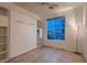 Bright bedroom with a built-in Murphy bed, shelving, neutral tile flooring, and natural light from the large window at 379 Fynn Valley Dr, Las Vegas, NV 89148