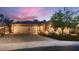 Charming home featuring a three-car garage, neutral stucco, stone accents, and a beautifully landscaped front yard at twilight at 379 Fynn Valley Dr, Las Vegas, NV 89148