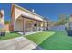 Landscaped backyard with an outdoor dining area, lounge seating, and artificial turf at 4211 Saxton Green Ave, Las Vegas, NV 89141