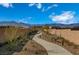 Curving walking path through desert landscaping with benches, retaining walls, and mountain backdrop under a bright blue sky at 4282 Yucca Brevi Ave, Las Vegas, NV 89139