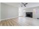 Bright living room featuring light wood floors, ceiling fan and a black brick fireplace at 4857 Fairfax Ave, Las Vegas, NV 89120