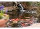 Charming koi pond with a small waterfall feature, surrounded by natural stone and greenery, enhancing the backyard's ambiance at 5050 Secret Rock St, Las Vegas, NV 89122