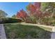 Back yard with grass, mature trees and stone perimeter at 605 Bachelor Button St, Las Vegas, NV 89138