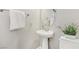 A well-lit half bathroom features a pedestal sink, oval mirror and decorative plants at 605 Bachelor Button St, Las Vegas, NV 89138