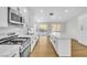 An open-concept kitchen featuring white cabinets, a tile backsplash, and stainless steel appliances at 6248 Spanish Moss Ave, Las Vegas, NV 89108
