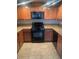 Well-lit kitchen with wooden cabinets, granite countertops, and a black oven and microwave at 6868 Sky Pointe Dr # 1034, Las Vegas, NV 89131