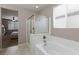 Bathtub and glass shower enclosure with tile flooring, neutral wall paint, and natural light from the window at 7525 Campbell Ranch Ave, Las Vegas, NV 89179