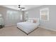 Bedroom features three windows, a ceiling fan, and a bed with soft white bedding and decorative pillows at 7525 Campbell Ranch Ave, Las Vegas, NV 89179