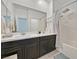 Bright bathroom featuring dual sinks, dark wood vanity, and a shower with tub at 788 Grand Country Ave, North Las Vegas, NV 89086