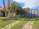 Landscaped front yard featuring lush green grass, a decorative driveway, and mature palm trees at 8504 Soneto Ln, Las Vegas, NV 89117