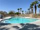Relaxing community pool area surrounded by palm trees, lounge chairs, and secure fencing at 9322 Straw Hays St # 101, Las Vegas, NV 89178