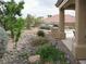 Charming backyard features rock landscaping, mature trees, shrubs, and a covered patio area with grill at 10112 Plomosa Pl, Las Vegas, NV 89134