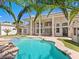 A stunning backyard with a sparkling pool, complemented by mature palm trees and architectural features on the home's facade at 1601 Fairgate Ct, Las Vegas, NV 89117