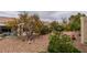 A gravel backyard featuring a young tree, various bushes, and chairs on a small deck at 2136 Eagle Sticks Dr. Dr, Henderson, NV 89012