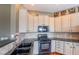 Well-lit kitchen featuring a black gas range, tile backsplash, and white cabinets at 217 Big Horn Dr # 3, Boulder City, NV 89005
