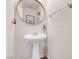 Compact powder room featuring a pedestal sink and a round mirror at 2504 Courlan Dr, North Las Vegas, NV 89084
