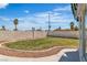 View of the green backyard showcasing a concrete perimeter, small rock garden, and a tall cement privacy wall at 3604 N Campbell Rd, Las Vegas, NV 89129