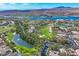 An aerial view of a housing community with golf course, landscaping, lake and mountain backdrop at 6 Rue Du Ville Way, Henderson, NV 89011