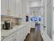 Hallway featuring white cabinets with gold hardware, leading to a modern kitchen and pantry at 6 Rue Du Ville Way, Henderson, NV 89011