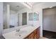 Bathroom with double sinks, white countertops, wood cabinets, and a view of the walk-in closet at 6476 Ness Gardens Ct, Las Vegas, NV 89122