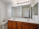 Bathroom with a double sink vanity, large mirror, and white tiled shower and toilet at 6476 Ness Gardens Ct, Las Vegas, NV 89122