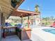 Outdoor kitchen with stainless steel grill by the pool, surrounded by seating and a lush green yard at 6540 Tara Ave, Las Vegas, NV 89146