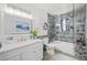 Well-lit bathroom with a modern vanity, decorative mirror, and a shower-tub combination with stylish tile surround at 6995 Rogers St, Las Vegas, NV 89118