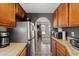 Galley kitchen features tile countertops, wooden cabinets, and stainless steel refrigerator at 6995 Rogers St, Las Vegas, NV 89118