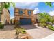 A two-story home features a dark garage door and desert landscaping, with a brick paved driveway at 7322 Dazzle Point St, North Las Vegas, NV 89084