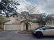 Two-story stucco home featuring a tile roof, arched entryway, two-car garage, and desert landscaping at 8226 Royal Lilly Ct, Las Vegas, NV 89139