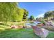 Peaceful pond with rock features, trees, and ducks swimming in the calm water under a sunny sky at 9005 Feather River Ct, Las Vegas, NV 89117