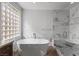 Bathroom featuring a soaking tub, glass enclosed shower, and decorative glass block window at 10537 Shoalhaven Dr, Las Vegas, NV 89134