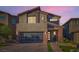 Stunning two-story home with a modern garage door, and stone accents, captured during a vibrant sunset at 10936 White Alder Pl, Las Vegas, NV 89138