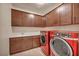 Well-lit laundry room featuring ample cabinet space, a sink, and a modern red washer and dryer set at 12283 Lost Treasure Ave, Las Vegas, NV 89138