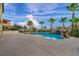 Expansive backyard featuring a sparkling pool with a rock waterfall, palm trees, and an inviting spa for relaxation at 12283 Lost Treasure Ave, Las Vegas, NV 89138